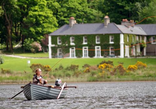 a woman is sitting in a boat in the water at Delphi Lodge in Leenaun