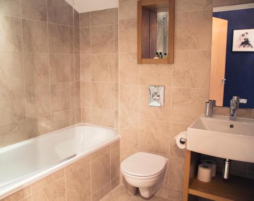 a bathroom with a toilet and a tub and a sink at Regent House deluxe 1 bedroom apartment in Harrogate