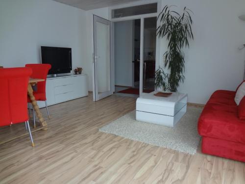 a living room with a red couch and a potted plant at Ferienwohnung Eisele in Buchenberg