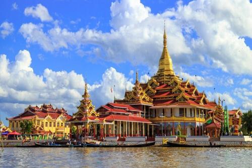 a group of pagodas on the water next to a building at 81 Hotel Inlay in Nyaung Shwe