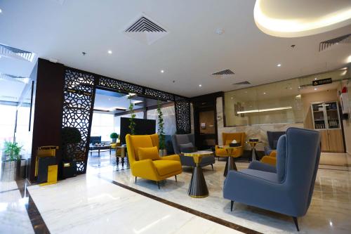 a lobby with yellow and blue chairs and tables at Bait Aldiyafah Hotel Apartments in Jeddah