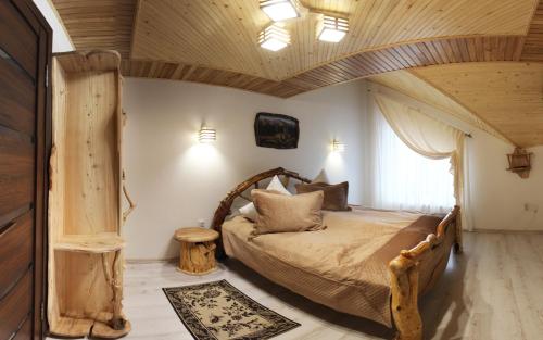 a bedroom with a large bed with a wooden ceiling at Cottage "Pyate Koleso" in Lazeshchyna