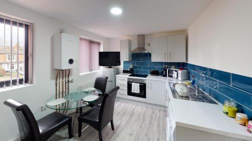 a kitchen with a glass table and a dining room at City Lodge Serviced Apartments Worcester City Centre - Parking in Worcester