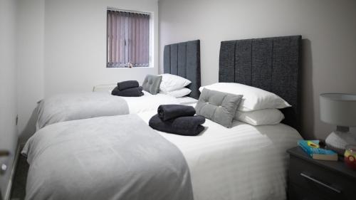 three beds in a room with white sheets and pillows at City Lodge Serviced Apartments Worcester City Centre - Parking in Worcester