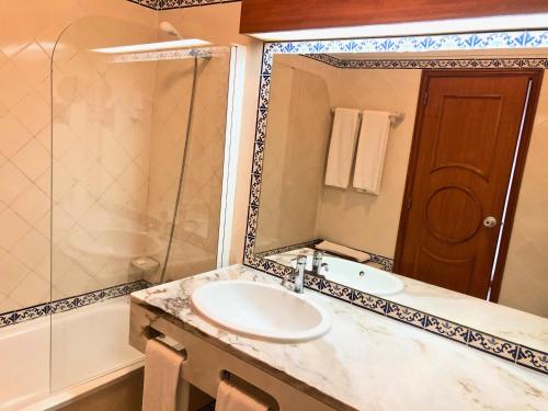 een badkamer met een wastafel, een douche en een spiegel bij Clube Oceano Apartments in Albufeira