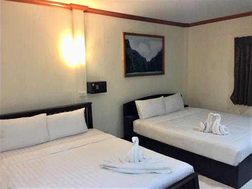 two beds in a hotel room with towels on them at Golden Bee PhiPhi in Phi Phi Don