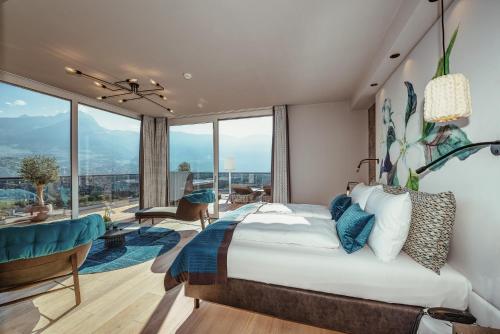een slaapkamer met een groot bed en een groot raam bij La Maiena Meran Resort in Marlengo