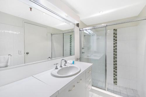 a white bathroom with a sink and a shower at Focus Apartments in Gold Coast