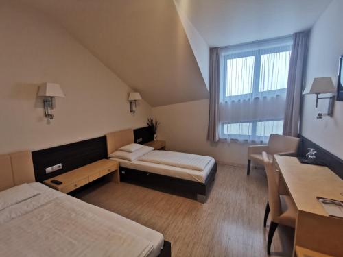 a hotel room with two beds and a desk at Gokart Hotel in Kecskemét