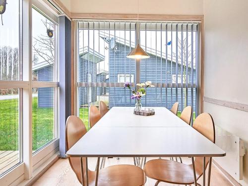 a dining room with a table and chairs and windows at 8 person holiday home in Gudhjem in Gudhjem