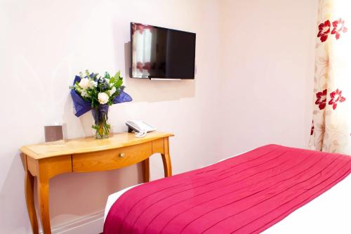a bedroom with a bed and a desk at Ellan Vannin Hotel in Douglas