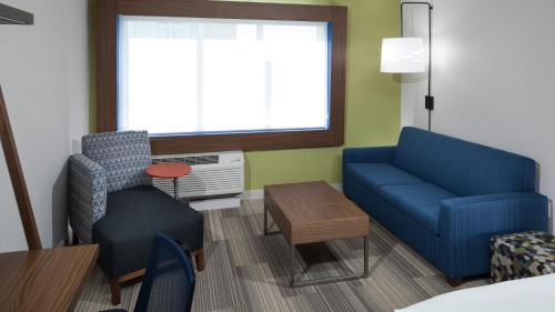 a living room with a blue couch and a table at Holiday Inn Express & Suites Orlando At SeaWorld by IHG - With Free Shuttle Service to SeaWorld Parks in Orlando