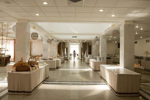 a lobby with white tables and a person in the distance at Санаторий Самшитовая роща in Pizunda