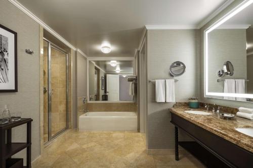 ein Badezimmer mit zwei Waschbecken, einer Badewanne und einer Dusche in der Unterkunft Hyatt Regency Huntington Beach Resort and Spa in Huntington Beach