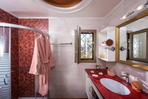 La salle de bains est pourvue d'un lavabo rouge et d'une douche. dans l'établissement Yiasemi Luxury Suite, à Mália