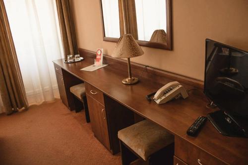a room with a desk with a phone and a mirror at Komfort Hotel Platan in Harkány