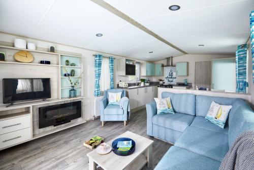 sala de estar con sofá azul y cocina en Siblu Camping de Oase, en Renesse