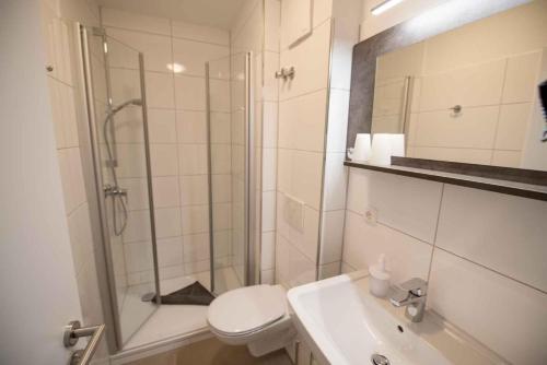 uma casa de banho com um chuveiro, um WC e um lavatório. em Ferienwohnung-2-Strandnah-und-mit-Strandkorb-im-Haus-Seeluft-in-Duhnen em Cuxhaven