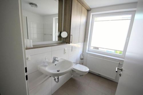 ein weißes Bad mit einem Waschbecken und einem WC in der Unterkunft Große Ferienwohnung 3 mit Meerblick und Strandkorb im Haus Seeluft Duhnen in Cuxhaven