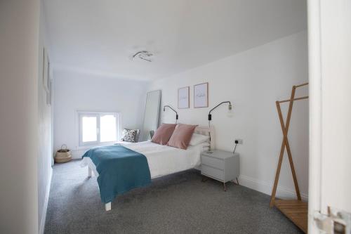 a white bedroom with a bed and a window at Sea Front Apartment in Saltburn-by-the-Sea