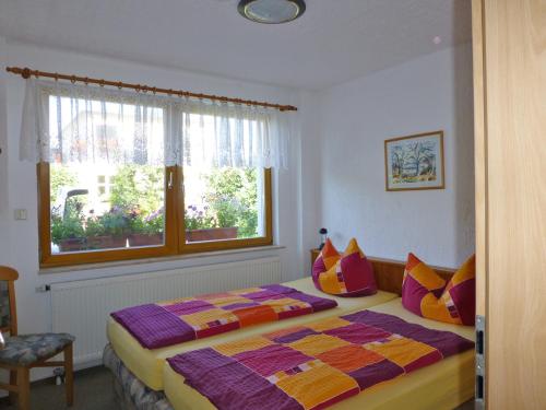 een slaapkamer met een bed met kleurrijke kussens en een raam bij Ostsee Ferienapartments in Graal-Müritz