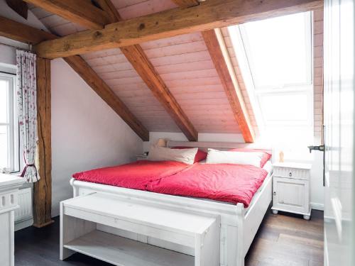 a bedroom with a white bed with a red comforter at Gut Royum in Brodersby