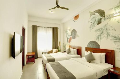 una habitación de hotel con 2 camas y un cuadro en la pared en Morven Hotel Colombo, en Colombo