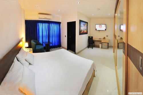 a hotel room with a white bed and a desk at Hotel Campestre El Cisne in Barranquilla