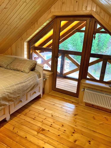 a bedroom with a bed and a large window at Терношорська Лада in Snidavka
