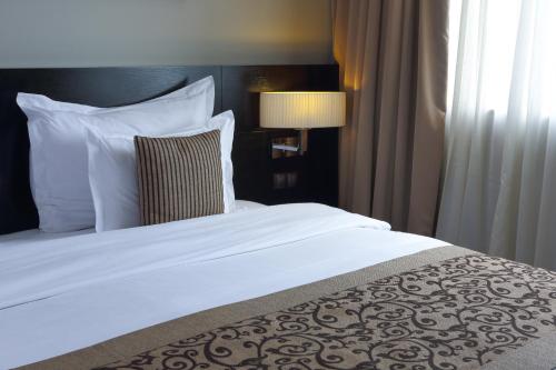 a bed with white sheets and pillows in a hotel room at Mövenpick Hotel Casablanca in Casablanca