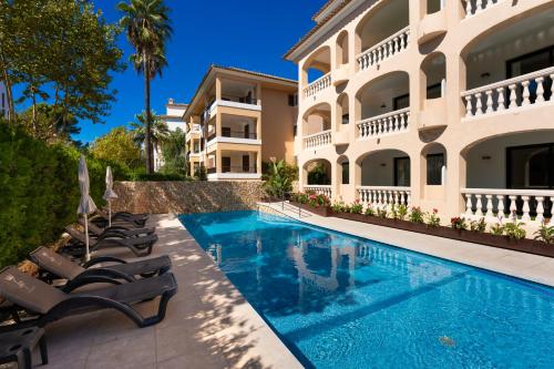 uma villa com piscina em frente a um edifício em Apartamentos S'Olivera em Canyamel