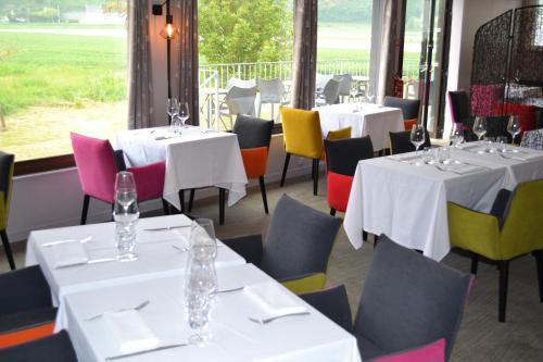un restaurant avec des tables blanches et des chaises colorées dans l'établissement The Originals Boutique, Hôtel Les Quatre Salines, Le Mont Saint-Michel Sud (Inter-Hotel), à Roz-sur-Couesnon