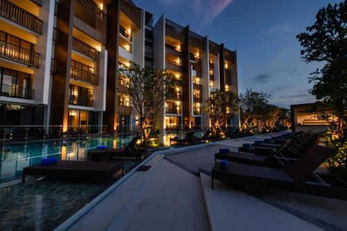 a hotel courtyard with chairs and a pool at night at iSanook Resort & Suites Hua Hin in Hua Hin
