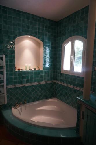 サリ・ソランザラにあるLa Villa Case Marineの緑のタイル張りのバスルーム(バスタブ付)、窓が備わります。