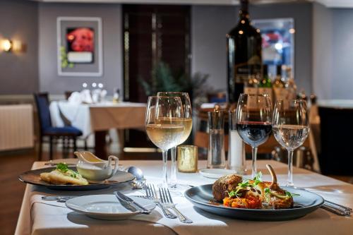 a table with two plates of food and wine glasses at Les Rocquettes Hotel in St Peter Port