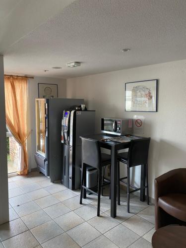 a dining room with a table and a refrigerator at Kimotel Epône-Flins in Épône