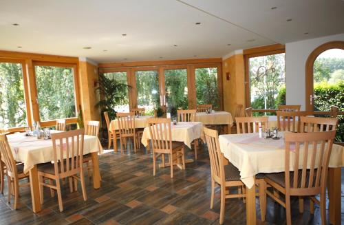 a restaurant with white tables and chairs and windows at Ute's Pension in Georgenberg