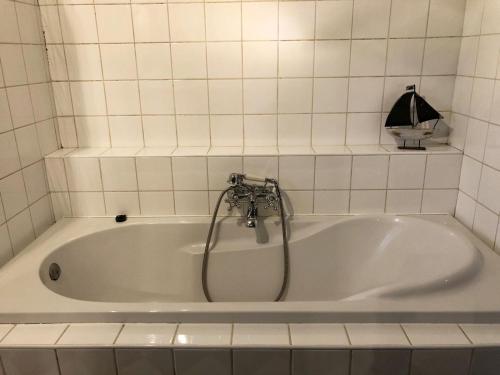 La salle de bains est pourvue d'une baignoire blanche et d'une douche. dans l'établissement Forest Guesthouse, à Bergentheim