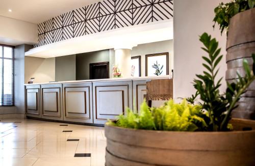 a lobby with a reception desk and a potted plant at Southern Sun Ridgeway Lusaka in Lusaka