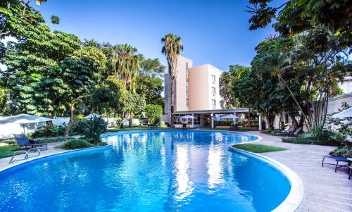 a swimming pool in a resort with palm trees at Southern Sun Ridgeway Lusaka in Lusaka