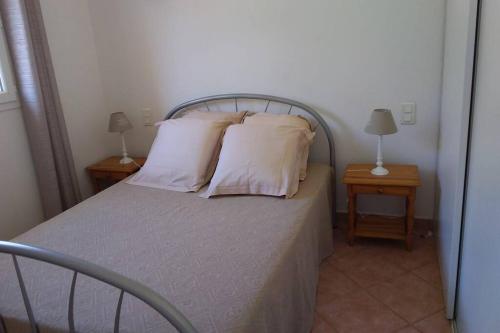 ein Schlafzimmer mit einem Bett mit Kissen und 2 Tischen in der Unterkunft SCALEDDA1 in Porto-Vecchio