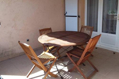 une table en bois avec quatre chaises et un réfrigérateur dans l'établissement Casa Louise 3 étoiles, à Porto-Vecchio