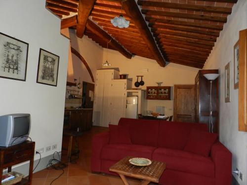 een woonkamer met een rode bank en een tv bij Angolo Alla Fortezza - Gigliola Contucci in Montepulciano