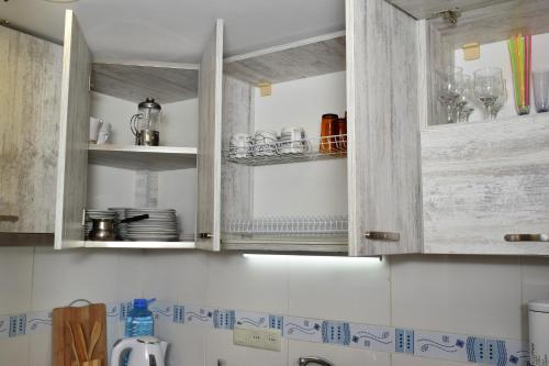 a kitchen with wooden cabinets with plates and glasses at Le Petit in Tbilisi City
