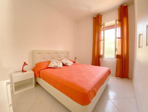 um quarto com uma cama com lençóis laranja e uma janela em Casa Vacanze Angelo em Palinuro