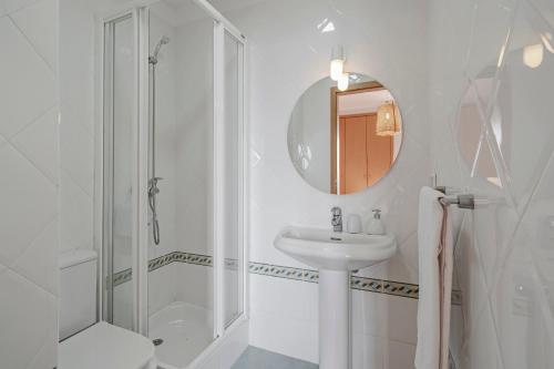 Baño blanco con lavabo y espejo en Garajau IV by An Island Apart en Caniço