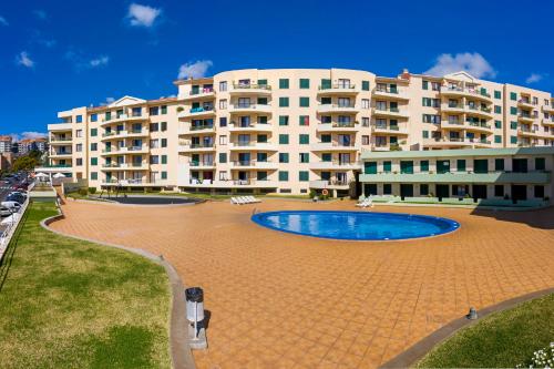 a large building with a swimming pool in front of it at Garajau IV by An Island Apart in Caniço