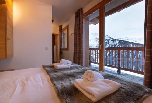 a bedroom with two towels on a bed with a balcony at Residence Miravidi La Rosiere in La Rosière