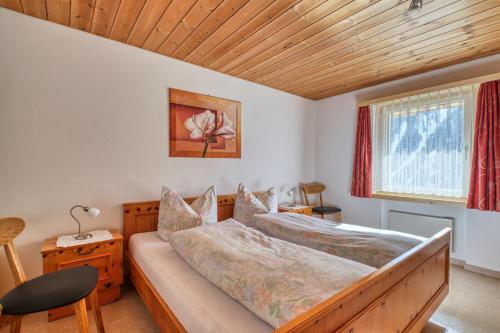 een slaapkamer met een bed en een houten plafond bij Chasa Plajet in Ramosch