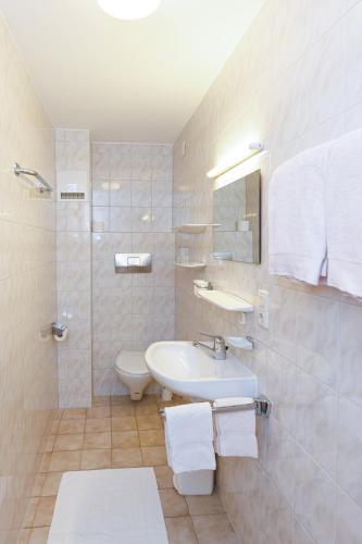 a white bathroom with a sink and a toilet at Haus Theresia in Mellau
